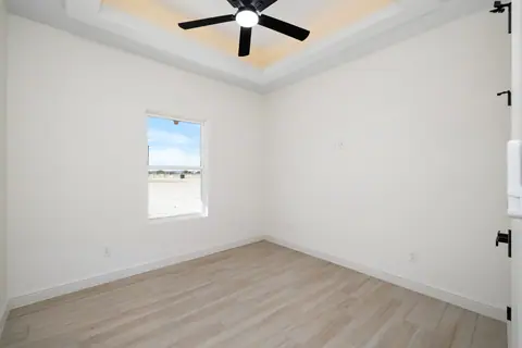 Bedroom with a ceiling fan, an LED tray and a wood-look floor