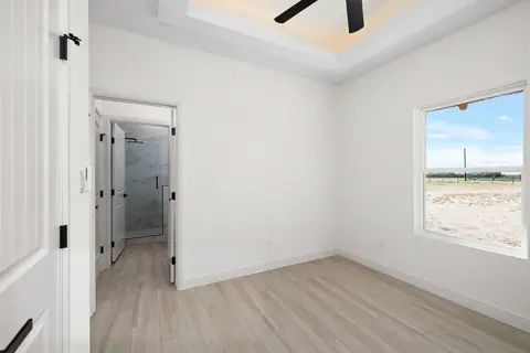 Bedroom with its own bathroom and a window facing open land