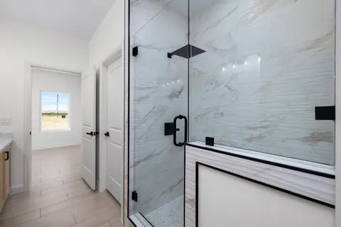 Glass shower with linear marble-look tile and matte black fixtures