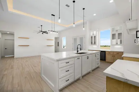 Kitchen with a white island, natural wood base cabinets and black hardware