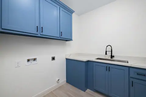 Laundry room with blue shaker cabinets and a utility sink