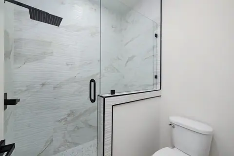 Bathroom with a glass shower, linear tile and black trim