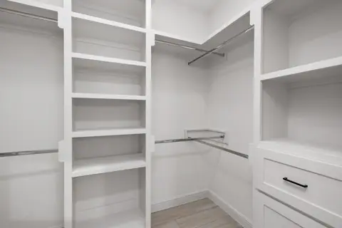 Walk-in closet with white built-in shelves and drawers