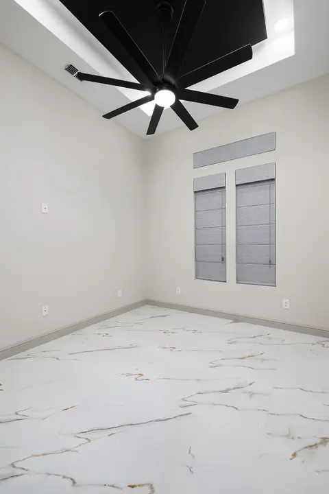 Bedroom with a black tray ceiling, a ceiling fan and a marble-look floor
