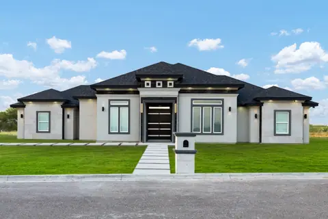 Casa contemporánea de stucco gris con techo de shingle gris oscuro a cuatro aguas y pasto nuevo
