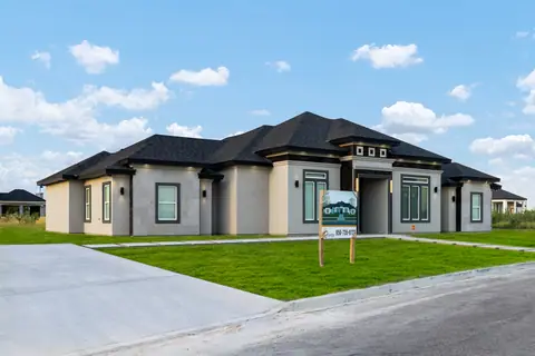 Gray stucco home with stone-look panels, a concrete driveway and wall sconces