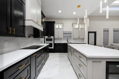 Cooktop wall and a long island with white counters and gold pulls