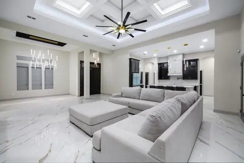 Open living and dining area with a coffered ceiling and a linear chandelier