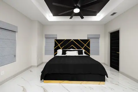 Primary bedroom with a black tray ceiling and a marble-look tile floor