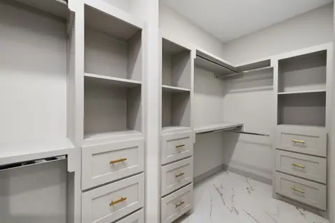 Walk-in closet with gray built-ins and gold drawer pulls