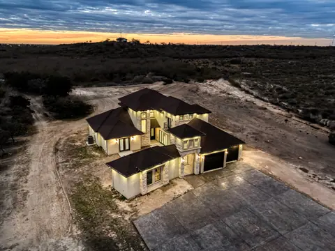 Aerial view at dusk of a stone and stucco home on a large rural lot