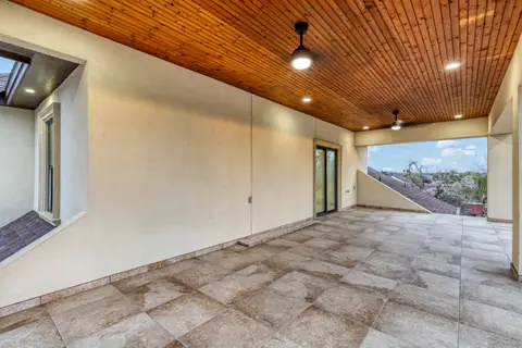 Covered upstairs balcony with a tongue and groove wood ceiling and a tile floor