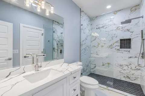 Bathroom with a marble-look glass shower and a black hexagon tile floor