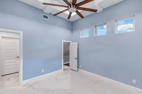 Blue bedroom with high clerestory windows and a ceiling fan