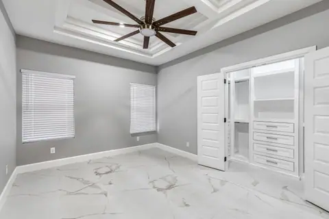 Gray bedroom with a tray ceiling and a closet with built-in drawers