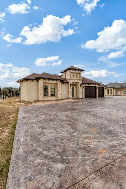Stamped and stained concrete driveway leading to a stone and stucco home