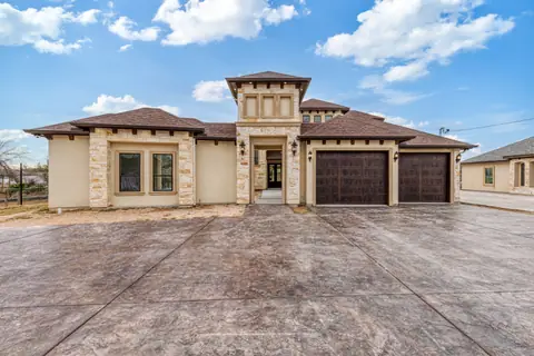 Stone and stucco home with a shingle hip roof, a three-car garage and a stamped concrete driveway