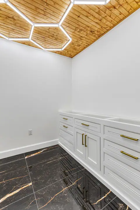 Cuarto con luces LED hexagonales en techo de pino y piso negro tipo mármol