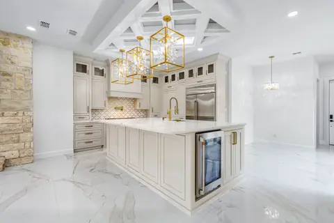 Kitchen island with a built-in wine fridge under a lattice ceiling with gold pendants