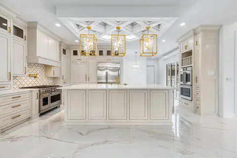 Kitchen with cream raised-panel cabinets, a large island, a professional-style range and gold hardware