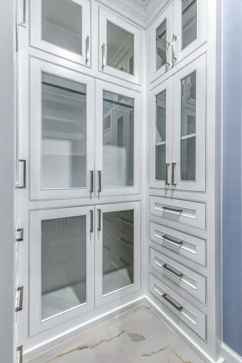 Gabinetes de blancos de piso a techo con puertas de vidrio y cajones