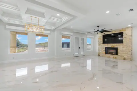 Living room with a coffered ceiling, a stone fireplace wall and wide windows