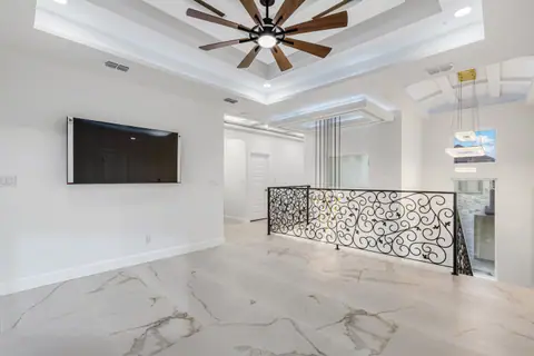 Upstairs loft with a scrolled iron railing over the stairwell and a lit tray ceiling