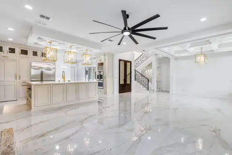 Open kitchen and living area with gold pendant lights, a long island and an iron stair railing