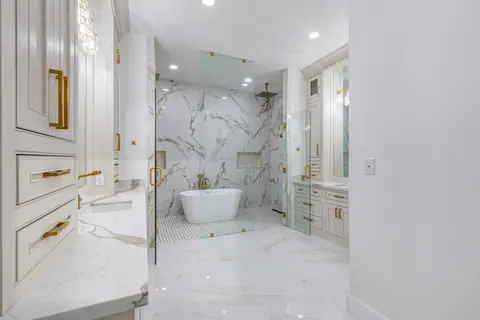 Primary bath with a freestanding tub inside a glass-enclosed wet room