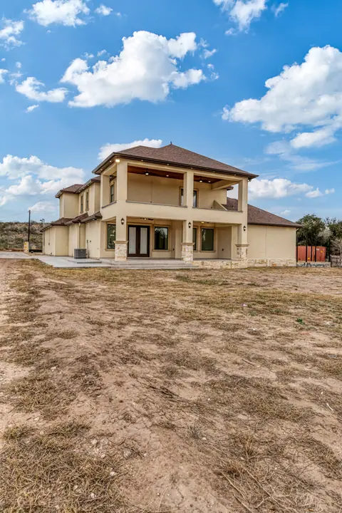 Covered back porch and upper balcony on a two-story stucco home