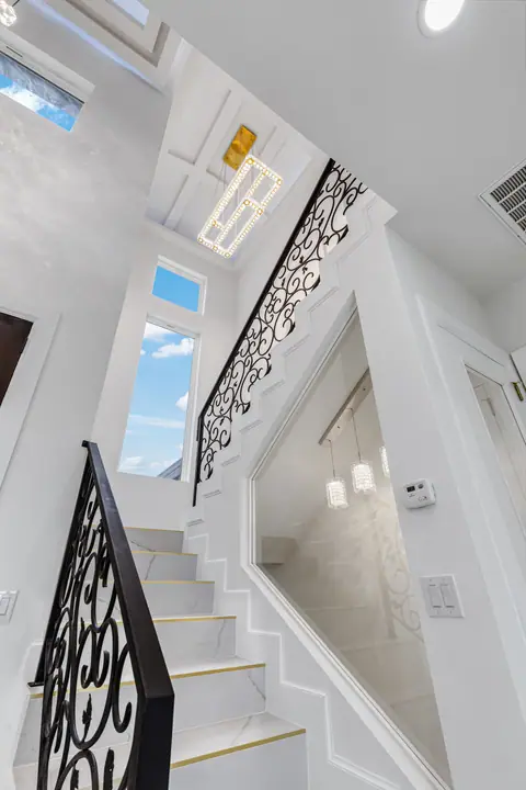 Staircase with a scrolled iron railing rising to the second floor