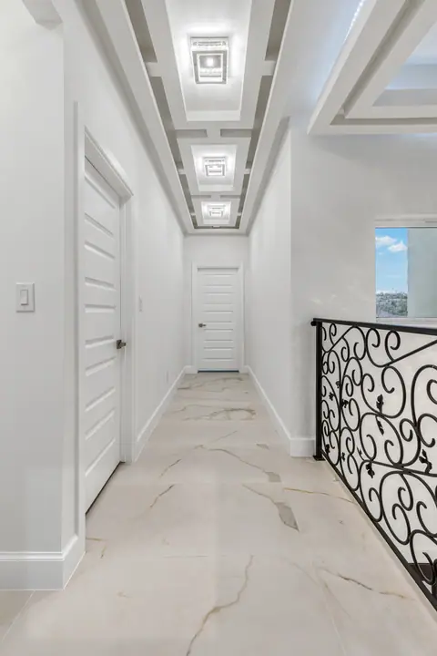 Pasillo del segundo piso con barandal de hierro y luces en el plafón