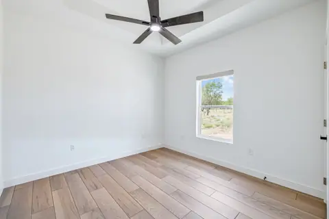 Secondary bedroom with a ceiling fan and wood-look flooring