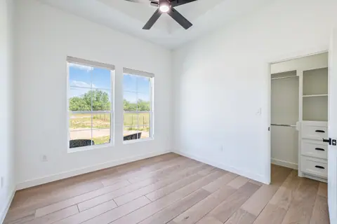 Bedroom with a walk-in closet and windows facing a wire ranch fence