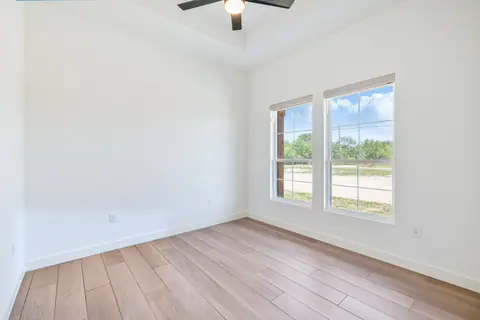 Bright bedroom with double windows and a ceiling fan in the tray