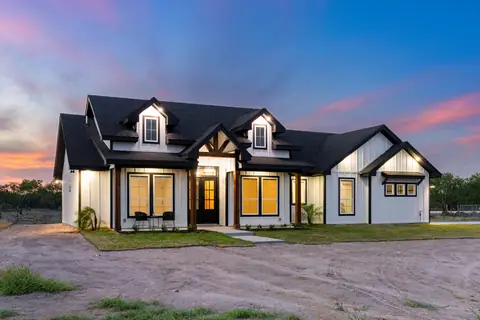 Front porch and gable details of a white farmhouse at sunset