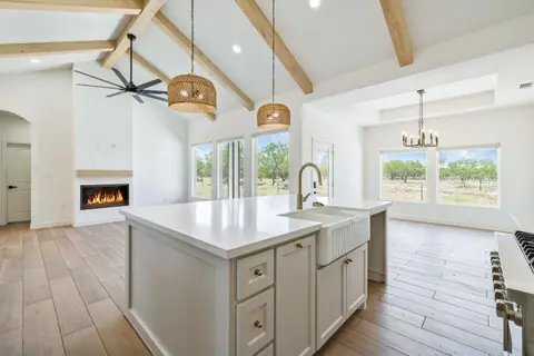 Farmhouse sink island, fireplace and dining area with windows toward the mesquite