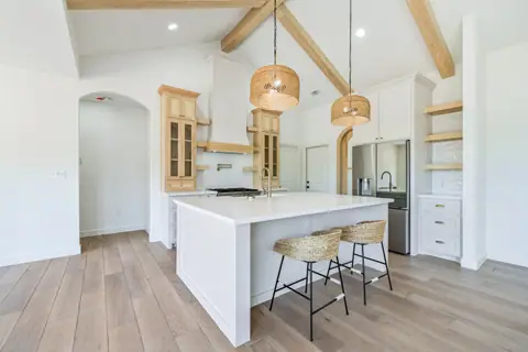 Farmhouse kitchen with a large white island and an arched doorway beyond