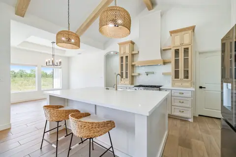 Island seating with glass-front natural wood cabinets and a white range hood