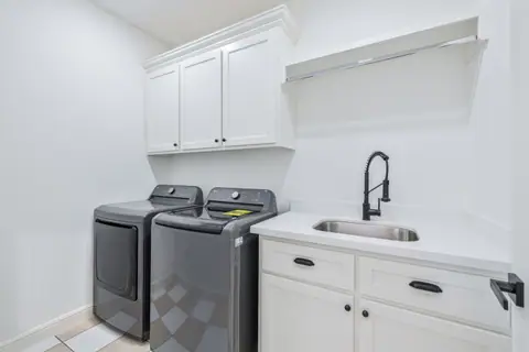 Laundry room with a utility sink, upper cabinets and a hanging rod