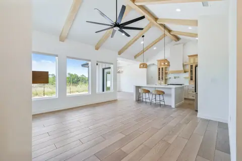 Vaulted living room with exposed wood beams opening into the kitchen