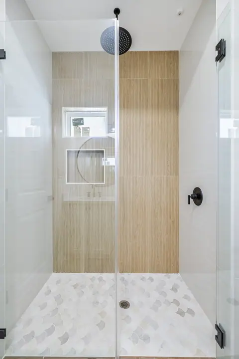 Regadera con muro de azulejo tipo madera y regadera de lluvia negra