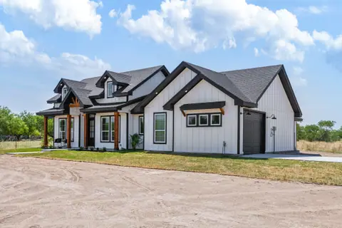 Side view of a white farmhouse with a side-entry garage and black-framed windows