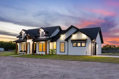 Board and batten siding and a black shingle roof lit at dusk