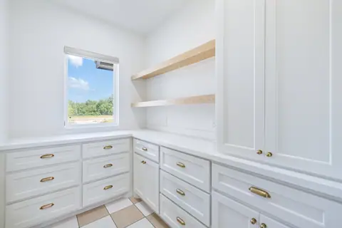 Utility room with white cabinets, floating wood shelves and a checkerboard tile floor