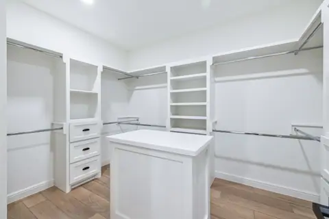 Walk-in closet with an island, drawers and double hanging rods